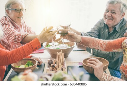 Happy Senior Couples Having Fun Cheering With Red Wine - Mature Friends Eating At Dinner And Laughing Together - Focus On Glasses - Joyful Elderly Lifestyle Concept - Vintage Retro Camera Filter