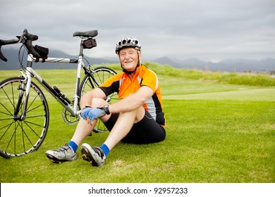 happy senior cyclist sitting on grass resting