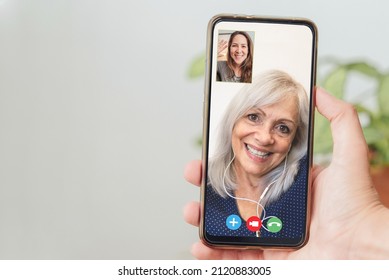 Happy senior and daughter talking on video call with mobile phone - Focus on hand holding smartphone - Powered by Shutterstock