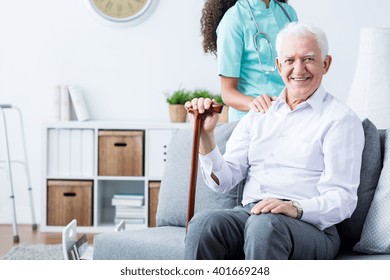 Happy Senior Disabled Man With Walking Stick And Caring Young Nurse