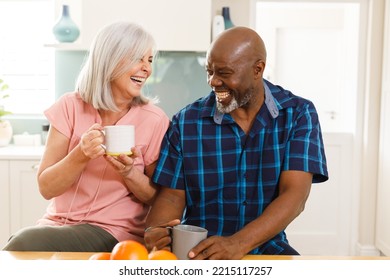 Happy senior diverse couple drinking coffee in kitchen. Spending quality time at home and retirement concept. - Powered by Shutterstock