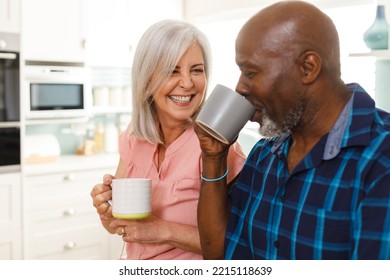 Happy senior diverse couple drinking coffee in kitchen. Spending quality time at home and retirement concept. - Powered by Shutterstock