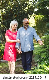 Happy Senior Diverse Couple Walking In Garden. Spending Quality Time At Home And Retirement Concept.