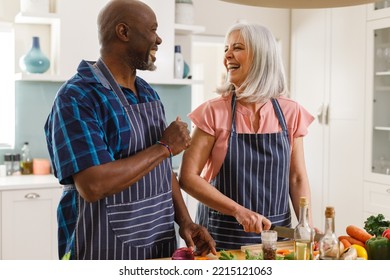 Happy senior diverse couple wearing aprons and cooking in kitchen. Spending quality time at home and retirement concept. - Powered by Shutterstock