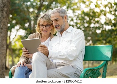 Happy Senior Elderly Couple Lifestyle Technology Chat Communication, Internet Video Call And Social Media By Tablet With Friend Or Family While Relax In Park On Holiday