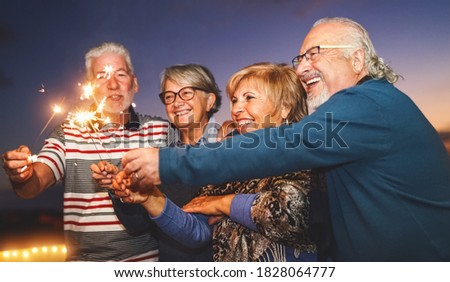 Happy senior family celebrating with sparkler fireworks at home party - Elderly people lifestyle and holidays concept 