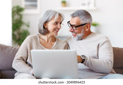 Happy senior family couple watching comedy funny video on laptop with smile on face while spending free time together at home on retirement, smiling retired husband and wife usinng modern technologies - Powered by Shutterstock