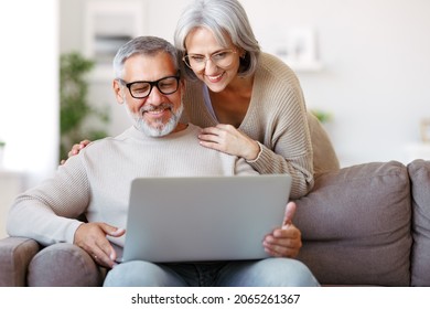 Happy senior family couple watching comedy funny video on laptop with smile on face while spending free time together at home on retirement, smiling retired husband and wife usinng modern technologies - Powered by Shutterstock