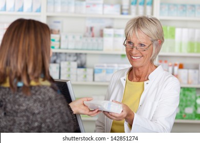 Happy senior female pharmacist giving prescribed medicine to customer in pharmacy - Powered by Shutterstock