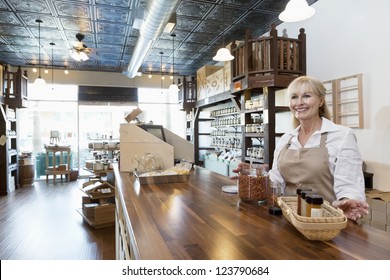 Happy Senior Female Spice Merchant Standing At Counter While Looking Away In Store