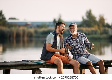 Happy senior fisherman and his adult son talking while having a drink on a pier. Copy space.  - Powered by Shutterstock