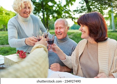 Happy Senior Friends Cheering With Glass Of Red Wine At Birthday Party