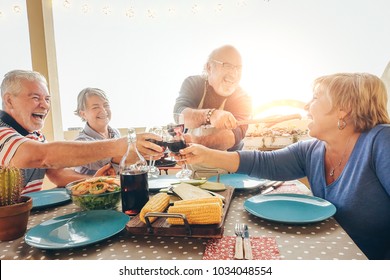 Happy Senior Friends Having Fun Cheering With Red Wine At Barbecue In Terrace Outdoor - Older People Dining With Grill Meat And Laughing Together - Friendship And Elderly Lifestyle Concept 