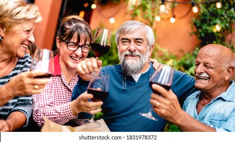 Happy senior friends having fun toasting red wine at dinner party - Retired people drinking at restaurant together - Dinning friendship concept on warm vivid filter - Focus on bearded hipster man - Powered by Shutterstock