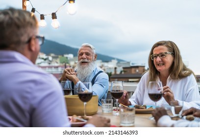 Happy senior friends having fun dining together on house patio - Elderly lifestyle people and food concept 