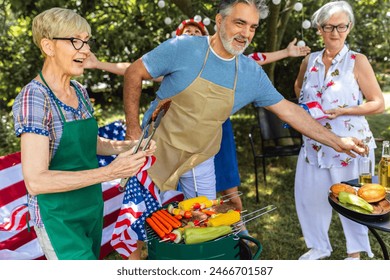 Happy senior friends having great time at at BBQ party. Elderly friends celebrating 4th of July outdoors with their friends and family. - Powered by Shutterstock