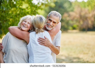 Happy Senior Friends Hugging Each Other In The Garden In Summer