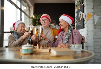 Happy senior friends sitting indoors in cafe clinking champagne glasses and celebrating Christmas. - Powered by Shutterstock