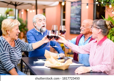 Happy Senior Friends Smiling  And Toasting Red Wine At Bar - Elderly People Eating At Restaurant - Drinking Lifestyle Concept - Focus On Blond Lady