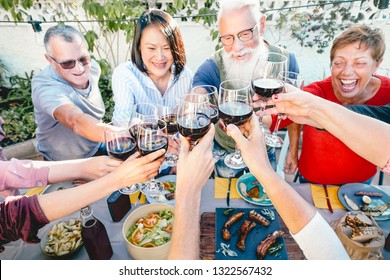 Happy Senior Friends Toasting With Red Wine Glasses At Dinner Time Outdoor - Mature People Having Fun Dining Together Outside - Elderly Lifestyle, Food And Drink, Retired And Pensioners Concept