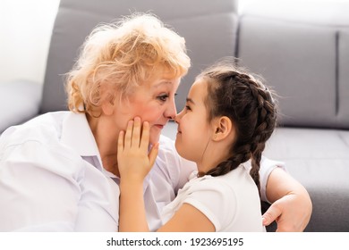 Happy senior grandmother sit on couch in living room hugging cute little preschooler granddaughter, smiling mature granny embrace cuddle with small grandchild, show love and care, bonding concept