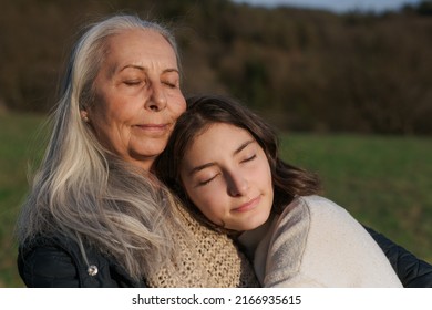 Happy senior grandmother with teenage granddaguhter hugging in nature on spring day. - Powered by Shutterstock