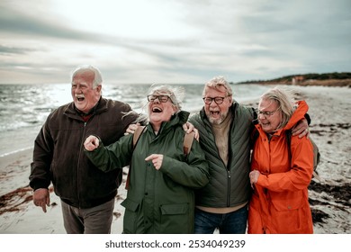 Happy senior group of friends walking on the beach on a windy day - Powered by Shutterstock