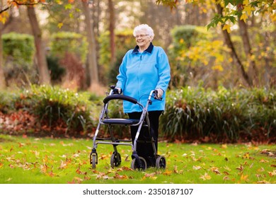 Feliz anciana discapacitada con una discapacidad para caminar disfrutando de un paseo en un parque de otoño empujando su caminante o silla de ruedas. Ayuda y apoyo durante la jubilación. Paciente de un centro de enfermería o de cuidados.