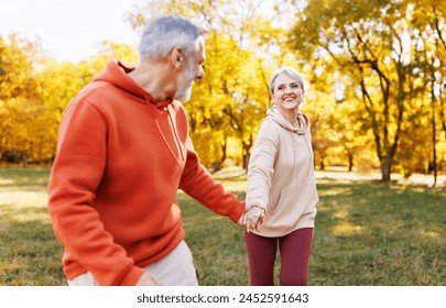 Happy senior husband and wife in sportive outfits running holding hands outdoors in city park, lovely retired couple jogging in sunny morning looking at each other with warmth and smile 
 - Powered by Shutterstock