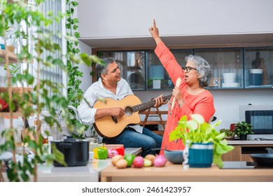 Happy senior Indian asian couple husband and wife have fun sing in kitchen appliances cooking together at home. - Powered by Shutterstock