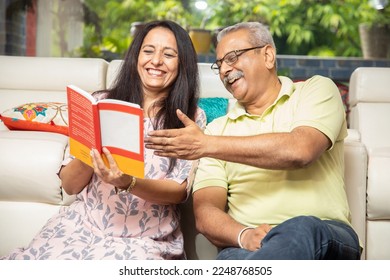 Happy senior indian couple reading book or novel together at home. 60s Retired husband wife spend time with each other and having fun. Retirement life. - Powered by Shutterstock