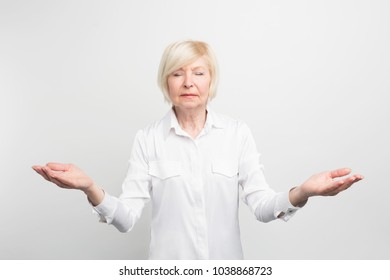 Happy senior lady meditating. She is searching for calm and trying to find herself. She wants to be hapy in her old age. Isolated on white background.