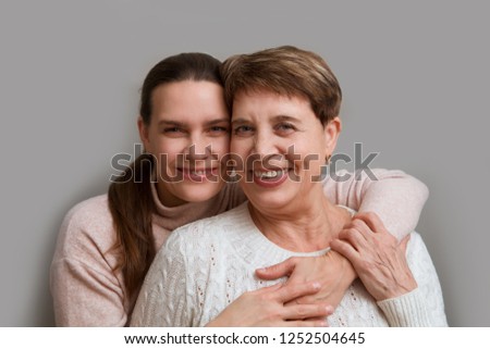 Elderly women embracing by the seaside, smiling together