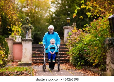 Happy senior lady with a walker or wheel chair and children. Grandmother and kids enjoying a walk in the park. Child supporting disabled grandparent. Family visit. Generations love and relationship.