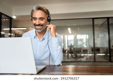 Happy senior latin Hispanic man in wearing headphones, helping as callcenter consult assistant. Smiling mature 40s years old mixed race businessman holding video call with clients partners. Copy space - Powered by Shutterstock