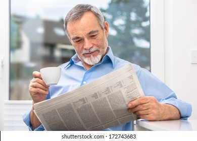 Happy senior man at breakfast with newspaper - Powered by Shutterstock