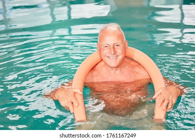 Happy Senior Man With Buoyancy Aid Doing Aqua Fitness In Rehab