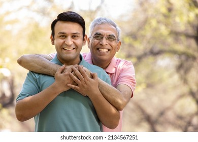 Happy senior man embracing adult son and admiring view at park
