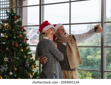 Happy Senior Man Embracing Couple And Taking Selfie Together With Mobile Phone, Standing Next To Decorated Christmas Tree In Cozy Living Room With Outside View Window In Winter. Merry Christmas.