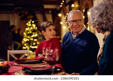 Happy senior man enjoying with his extended family during Christmas dinner at dining table.  - Powered by Shutterstock