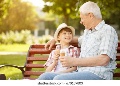 Happy senior man enjoying spending time with his grandson outdoors at the park eating ice cream together copyspace family leisure lifestyle parenting children love weekend summer holidays food concept - Powered by Shutterstock