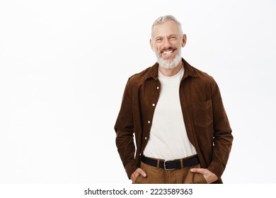 Happy senior man with grey hair and beard, smiling white teeth, looking confident and carefree, posing against studio background. - Shutterstock ID 2223589363