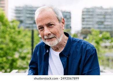 Happy senior man with grey hair and beard smiling at camera standing over urban background. Outside portrait of pensioner male. - Powered by Shutterstock