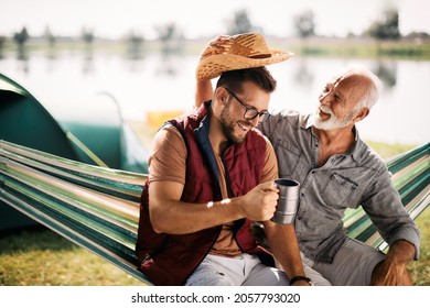 Happy senior man having fun with his adult son while camping together by the lake. - Powered by Shutterstock