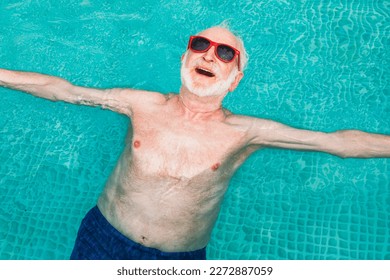 Happy senior man having party in the swimming pool - Active elderly male person sunbathing and relaxing in a private pool during summertime - Powered by Shutterstock