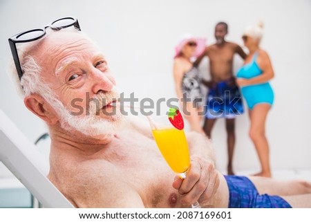 Happy senior man having party in the swimming pool - Active elderly male person sunbathing and relaxing in a private pool during summertime
