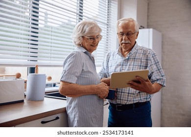 Happy senior man and his wife surfing the net on digital tablet in the kitchen.  - Powered by Shutterstock