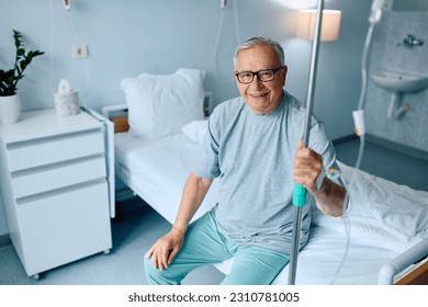 Happy senior man with IV drip sitting on hospital bed and looking at camera.  - Powered by Shutterstock