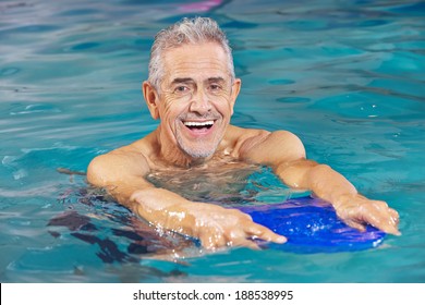 Happy senior man with kickboard in water of swimming pool
