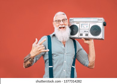 Happy senior man listening to music with boombox outdoor - Crazy hipster male having fun dancing with vintage stereo - Concept of elderly people lifestyle